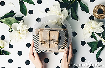 Flat lay arrangement female`s hands holding gift boxes among presents and flowers Stock Photo