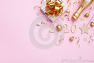 Flat lay background for Christmas and New Year. Champagne bottle, golden gift or present box, 2020 number and confetti on pink Stock Photo