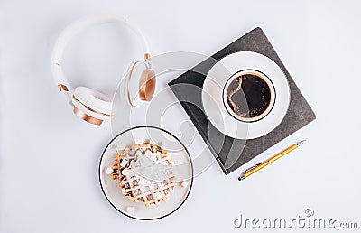 Flat lay of Belgian waffles with marshmallows and coffee, headphones and notebook on white background. Top view Stock Photo