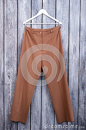 Flat lay brown woman trousers on hanger. Stock Photo