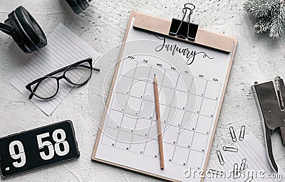 Flat lay of a calendar diary, flip clock screensaver on the phone, stapler, headphones, and pencil Stock Photo