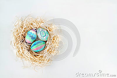 Flat lay of colorful Easter eggs in nest. Easter eggs colored with blue and green paint in various patterns. Stock Photo