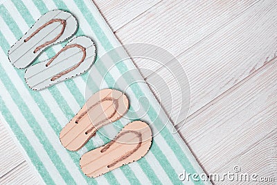 Flat lay of composed miniature of beach lounge area with summer shoes - two pair flip-flops, terry towel Stock Photo