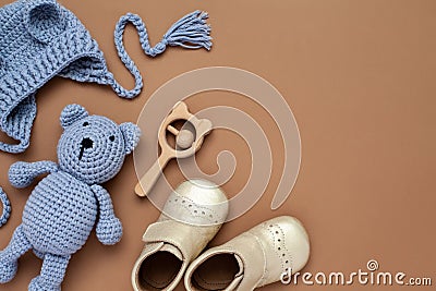 Flat lay composition with baby accessories set: crib shoes, teddy bear toy, knitted hat, wooden rattle and copy space. Stock Photo
