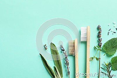 Flat lay composition with bamboo toothbrushes and herbs on turquoise background. Space for text Stock Photo