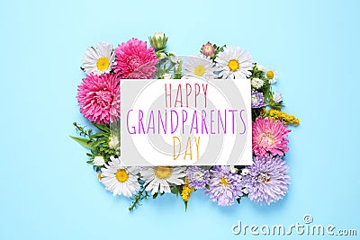 Flat lay composition with aster flowers and phrase HAPPY GRANDPARENTS DAY on light blue background Stock Photo