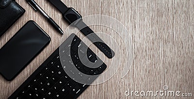 Flat lay composition with black pen, computer keyboard, smart watch, smartphone and leather wallet on a wooden surface. Business Stock Photo