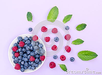 Flat lay composition of bowl with raspberries and blueberries and plenty of different berries and fresh green mint leaves as a Stock Photo