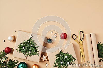 Flat lay composition with Christmas gifts decorated fir branches, scissors, wrapping paper, baubles on beige table Stock Photo