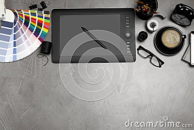 Flat lay composition with graphic drawing tablet and office items on grey stone background, space for text. Designer`s Stock Photo