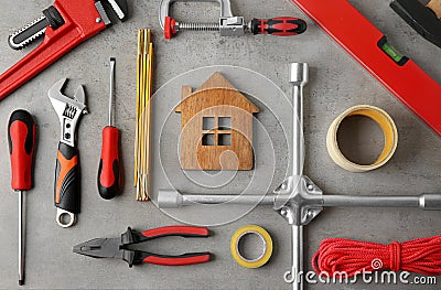 Flat lay composition with house figure and repair tools on stone table Stock Photo