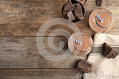 Flat lay composition with jars of tasty chocolate milk and space for text on wooden background. Stock Photo