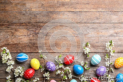 Flat lay composition with painted Easter eggs and blossoming branches on wooden background. Stock Photo