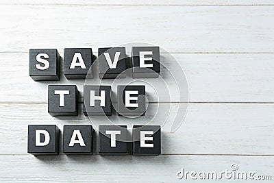 Flat lay composition with phrase SAVE THE DATE made of black cubes on wooden background Stock Photo