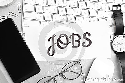 Flat lay composition with word JOBS, computer keyboard and smartphone on grey marble table. Career concept Stock Photo