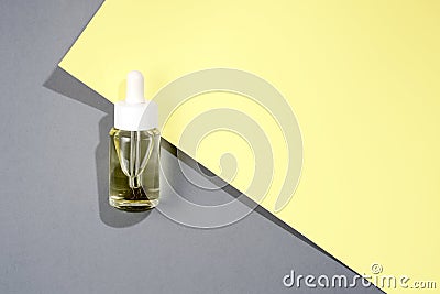 flat lay cosmetic transparent bottle with oil on grey and yellow background Stock Photo