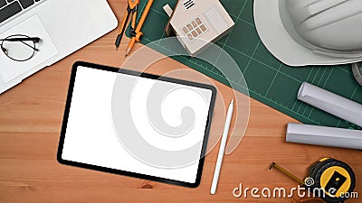 Flat lay digital tablet, blueprints, helmet, house model and tools on wooden table. Engineer, Architect workspace Stock Photo