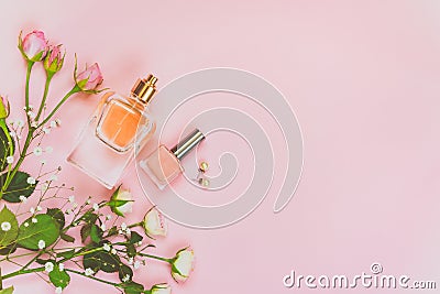 Flat lay of female cosmetics products and accessories. A bottle of perfume, nude nail polish, pearl earings and roses over pink ba Stock Photo