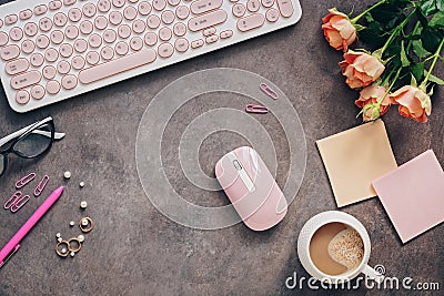 Flat lay female workspace - modern keyboard, mouse, cup of coffee, rose flowers, jewelry and stationery on a dark rustic Stock Photo