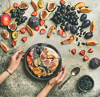 Flat-lay of Greek yogurt, fruit, chia seeds bowl in hands Stock Photo