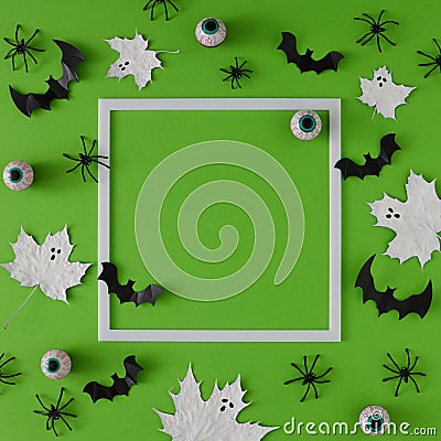 Flat lay Halloween background made with leaves painted in white like ghosts, bats and eyeballs. Stock Photo