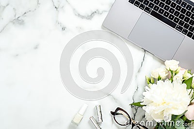 Flat lay home office desk. Female workspace with laptop computer, white flowers bouquet, accessories, cosmetic on marble Editorial Stock Photo