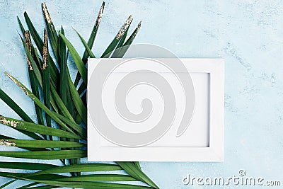 Flat lay horizontal photo frame mock up with green and gold palm leaves on blue background. Travel concept Stock Photo