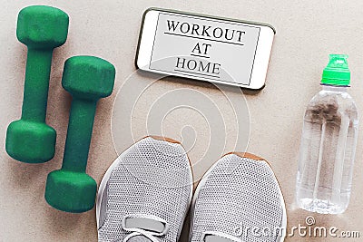 gray sneakers, green dumbbells, bottle of water, and a smartphone Stock Photo