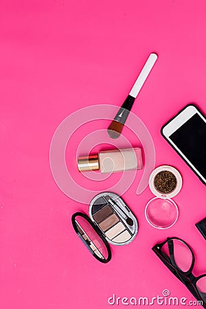 Flat lay of makeup products smartphone and women glasses on a rich pink paper background Stock Photo