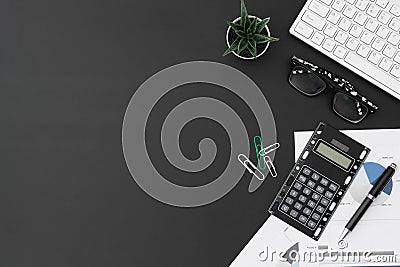 Flat lay office desktop work space of wireless keyboard, report graph and charts, pen, calculator and Glasses on black desk table Stock Photo