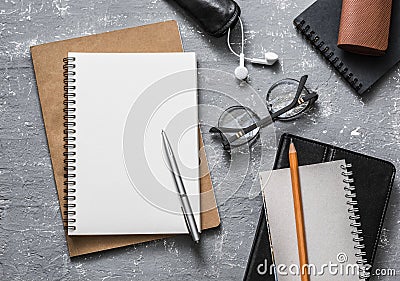 Flat lay office workplace. Business or education accessories - blank notepad glasses, pens, pencils, headphones on grey background Stock Photo