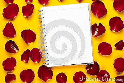 FLAT LAY open notebook lies on rose petals. Yellow background Stock Photo