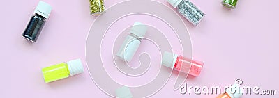 A flat lay pattern with colorful glitter bottles lies on pastel pink background Stock Photo