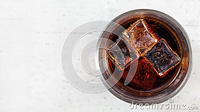 Flat lay photo, glass with cola, bubbles around ice cubes, on white working board, space for text left side Stock Photo