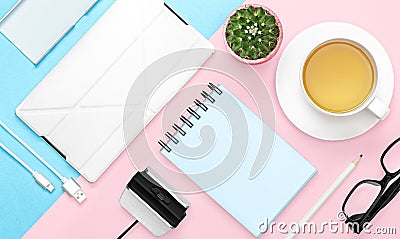 Flat lay photo of office desk with case for phone and tablet, notebook, tea mug, pencil, cactus, pink and blue background Stock Photo