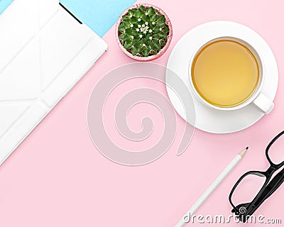 Flat lay photo of office desk with tablet computer, tea mug, pencil, cactus, glasses, pink and blue background Stock Photo