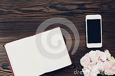 Flat lay pink flowers, mobile phone and diary on wooden background, top view. mock up Stock Photo