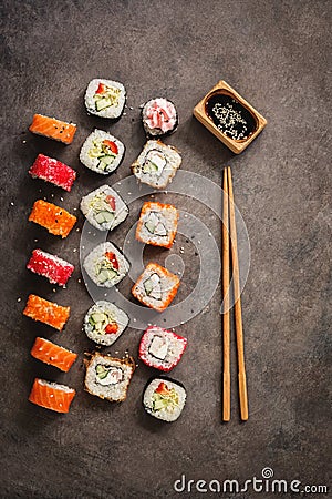 Flat lay rows of sushi rolls, soy sauce and chopsticks on a dark rustic background. View from above. Traditional asian food Stock Photo