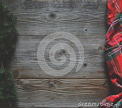 Flat lay of scarf with Christmas tartan texture and branch of tree on wooden background with space in middle - Christmas or New Stock Photo