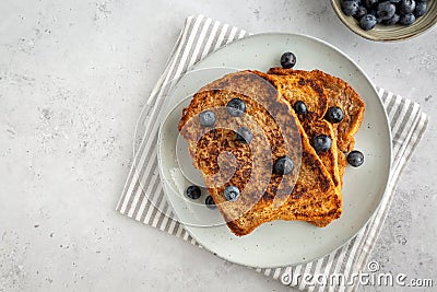 Flat lay of three slices of french toast with blueberries on a plate on grey background, copy space on the left Stock Photo