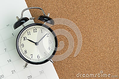 Flat lay or top view of black alarm clock with white calendar on wooden pin board with copy space, schedule for vacation, Stock Photo