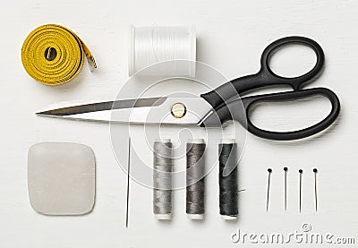 Flat lay top view sewing tools with measurement tape, chalk, thread, needles and scissors on white wood table Stock Photo