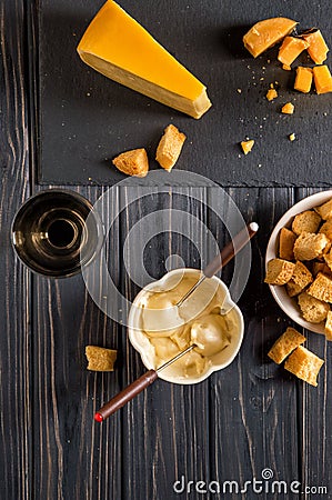 Flat lay. Traditional french cheese fondue. Crouton dipped into hot cheese fondue on a long-stemmed fork. Stock Photo