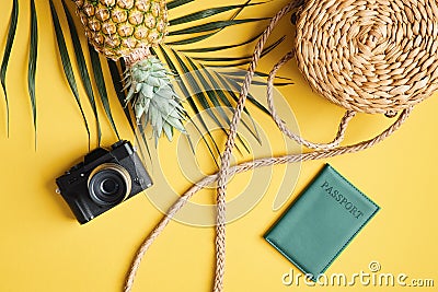 Flat lay traveler accessories on yellow background. Top view palm leaf, camera, rattan straw bag, pineapple and passport. Travel, Stock Photo