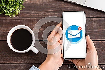 Flat lay of woman holding smartphone with email envelope on screen, using mobile app to manage incoming mail messages Stock Photo