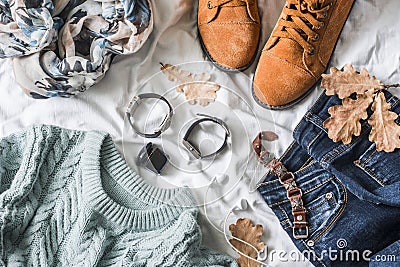 Flat lay women`s clothing for autumn walks, top view. Brown suede boots, jeans, a blue pullover, scarf, bracelets, watches, headp Stock Photo