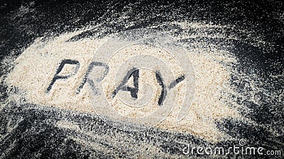 Flat lay of word PRAY written on white sand Stock Photo
