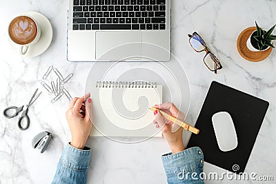 Flat lay workspace. Woman hand with coffee cup, smartphone, computer, notebook, planner and stationary with copy space on marble Stock Photo