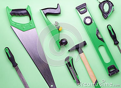 Flat layout: a set of hand tools for construction and repair on a green background. Stock Photo