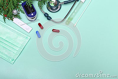 Flat medical top view plan of stethoscope, pulse oximeter, express test and christmas decorations on green background, copy space Stock Photo